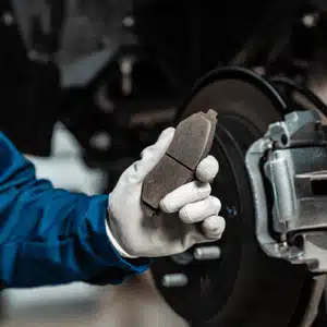 Mechanic holds worn component to explain replacement timing for Mercedes brake pads clearly