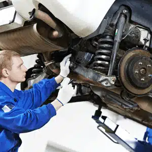 A technician evaluates rear land rover suspension damage while lifting the vehicle for access
