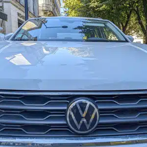 The front view of a parked white Volkswagen car shows its grille and shiny emblem