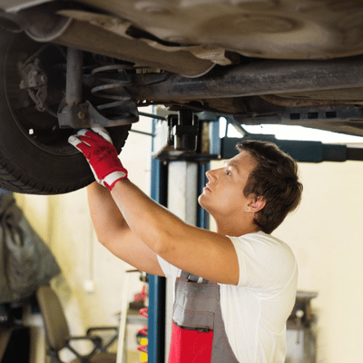 Mechanic working on Land Rover wheel area to diagnose and fix land rover air suspension problems