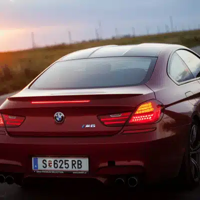 Red performance coupe drives at dusk, quad exhaust tips visible, highlighting sporty design features exterior