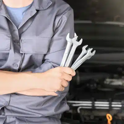 Technician holds wrenches beside open engine bay preparing for mercedes auto repair work today