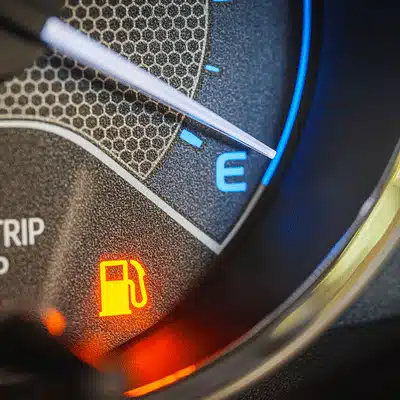 Close-up dashboard fuel gauge near empty at Mercedes-Benz service center, showing illuminated gas icon warning