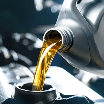 Fresh motor oil pours into an engine fill port, showing routine maintenance during land rover servicing