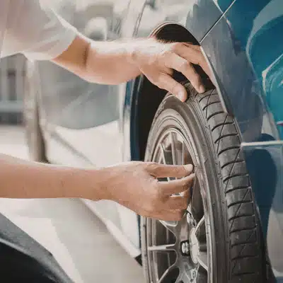 A mechanic inspects a tire and wheel by hand, confirming tread and pressure during land rover servicing